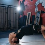 Man performing a back bridge stretch in a gym, emphasizing flexibility and fitness.